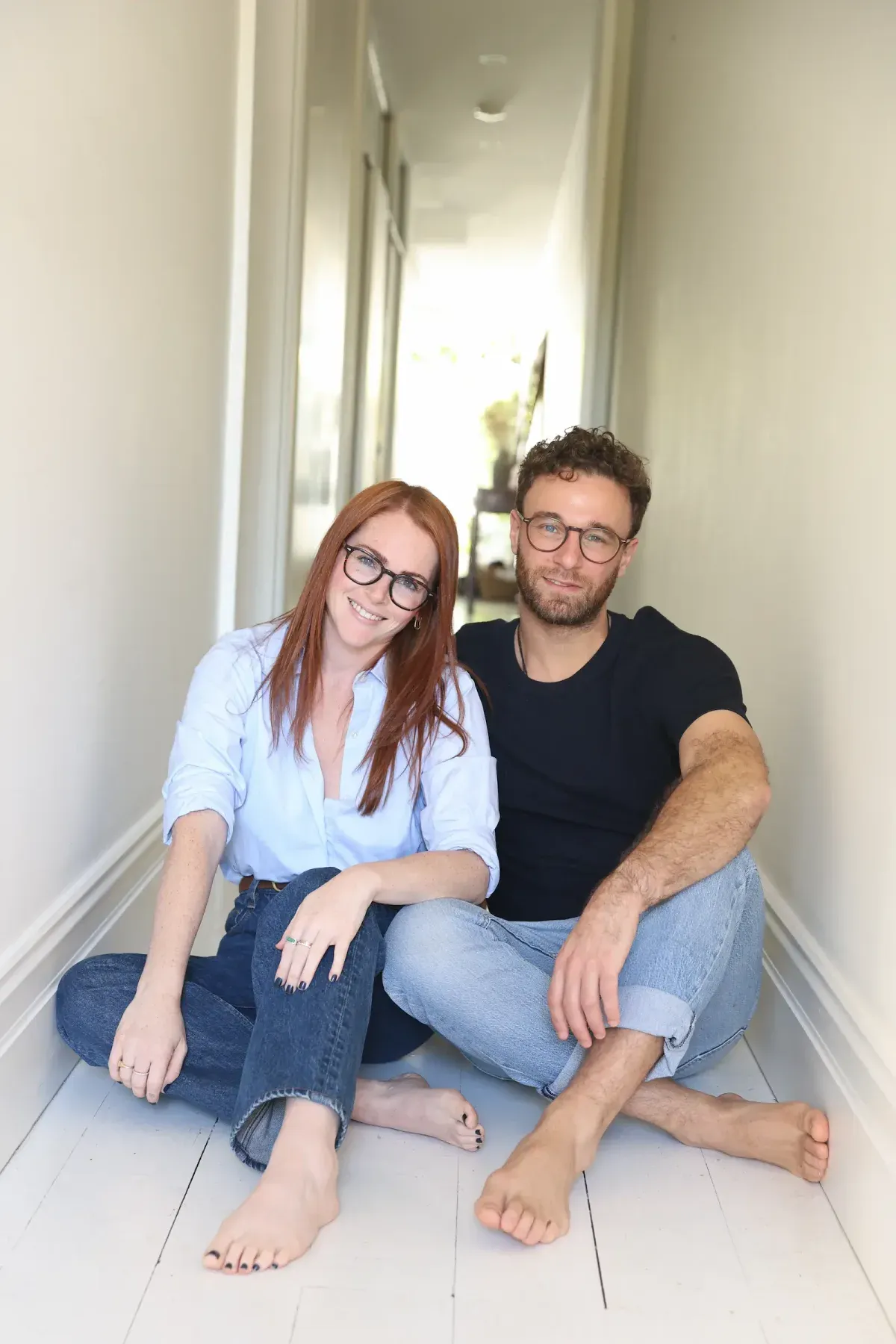 Tammy and Daniel seated in a hallway, a warm and grounded portrait of the Soma + Soul practitioners